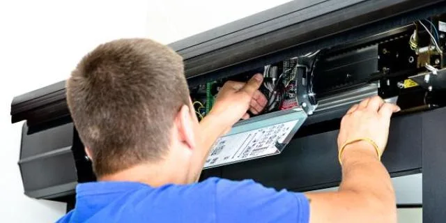 Muž opravuje motor automatických posuvných vrat.