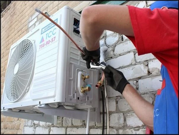 Technik odpojuje měděné hadice z venkovní jednotky klimatizace.