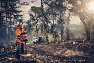 Lesní dělník opravuje řetězovou pilu značky Husqvarna nebo Stihl.