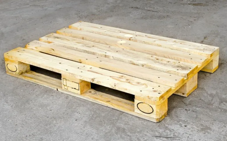 Jednoduchá dřevěná paleta na betonové podlaze pro ilustraci.