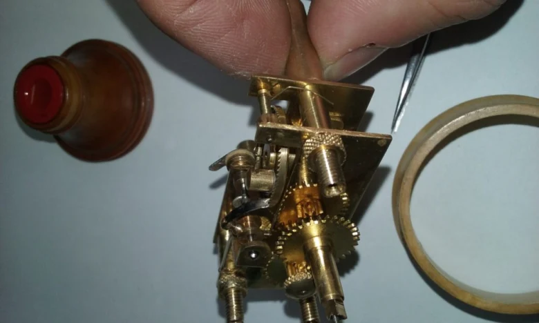 Ruce sestavují zlatý mechanismus mechanických nástěnných kyvadlových hodin.
