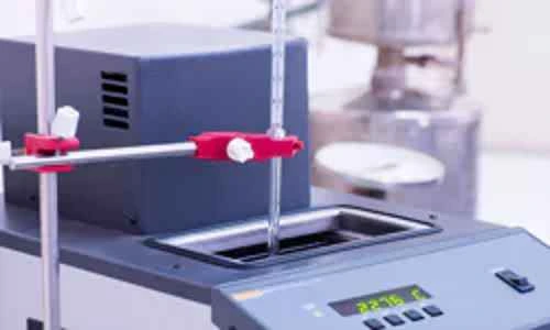 Laboratorní teploměr s digitálním displejem v kalibrační lázni.