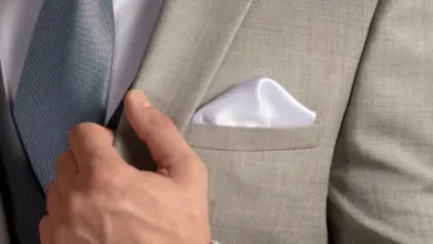 Muž v šedém obleku s modrou kravatou a bílou kapesníkem.
