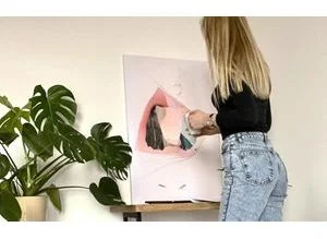 Žena visí obraz na zeď pomocí lepicích proužků bez vrtání.
