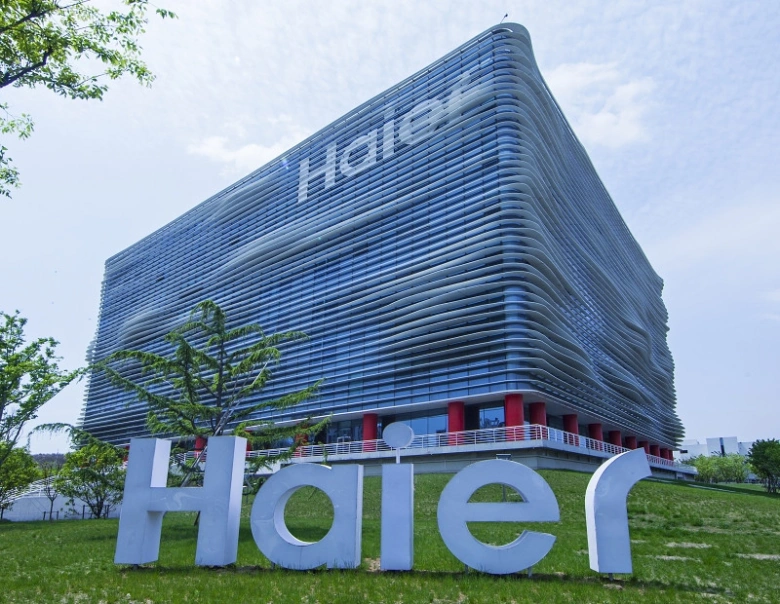 Modern budova společnosti Haier s velkým logem na trávníku.