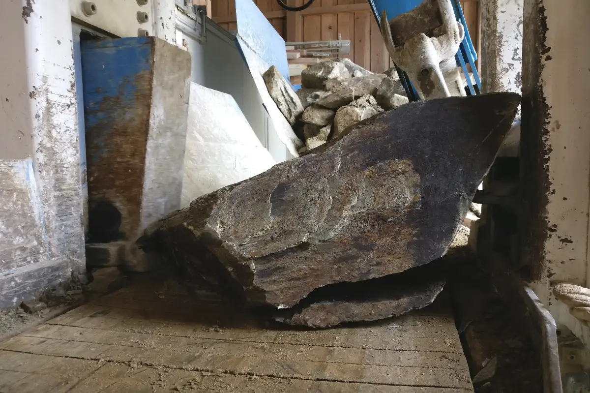 Velký kámen mezi strojem na štípání kamene v dílně.