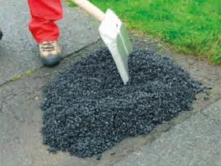Kopírování studeného asfaltu lopatou na povrch silnice.
