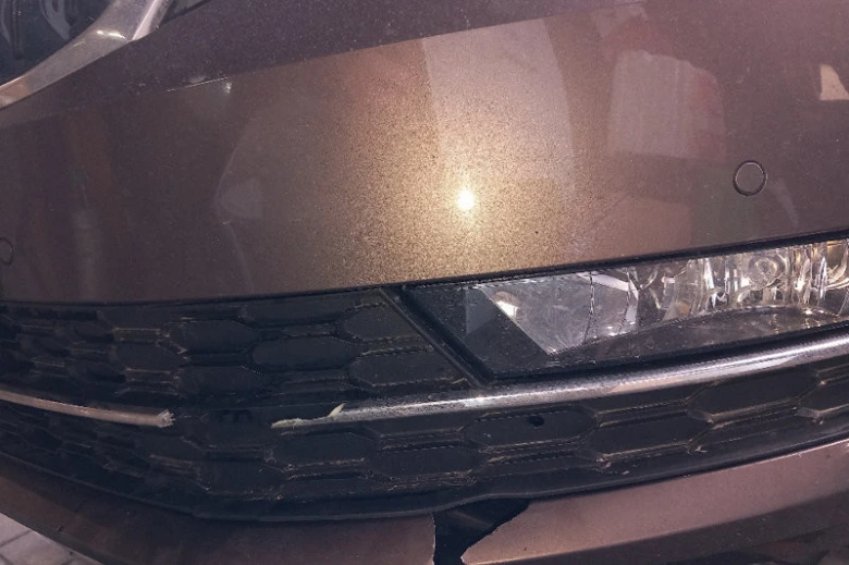 Poškozený nárazník automobilu s prasklinami v dolní části.