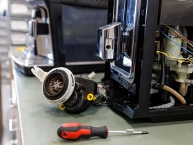 Rozložený televizor s odšroubovanými díly na pracovním stole.