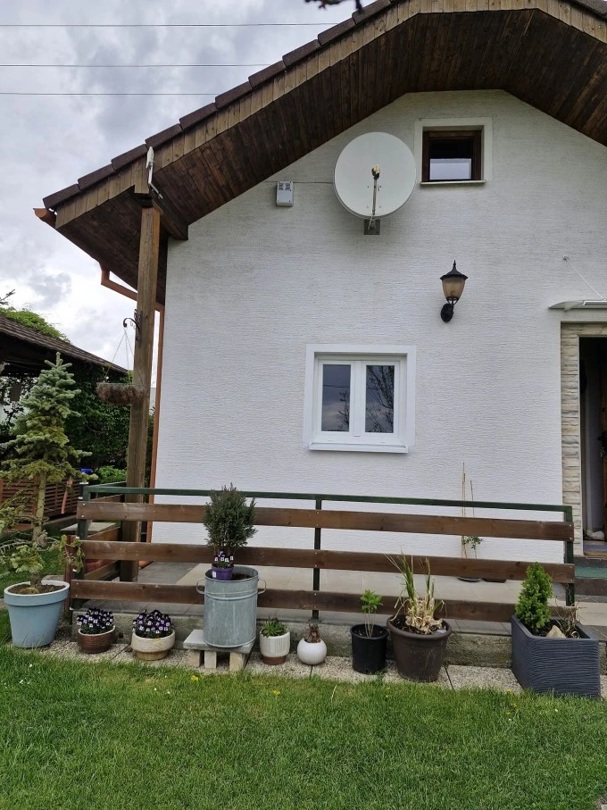 Bílý dům s okny a květinami na schodišti.