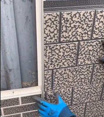 Instalace dekorativních nástěnných panelů vedle okna rukou v gumové ruce.