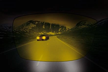 Auto na silnici v noci skrze žluté antireflexní brýle.