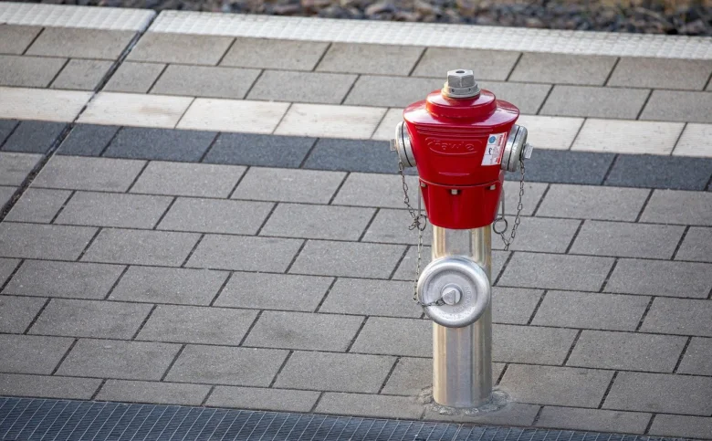Červený požární hydrant na chodníku z dlažby.