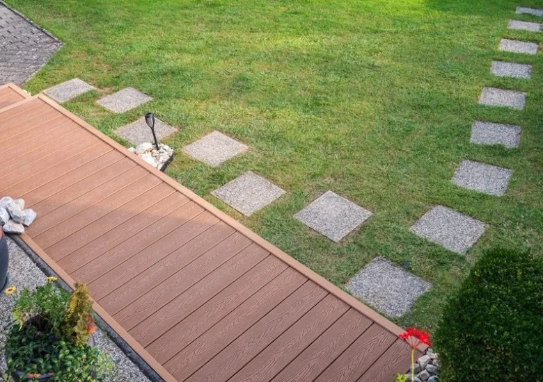 Hotová dřevěná terasa z kompozitového materiálu vedle trávníku.