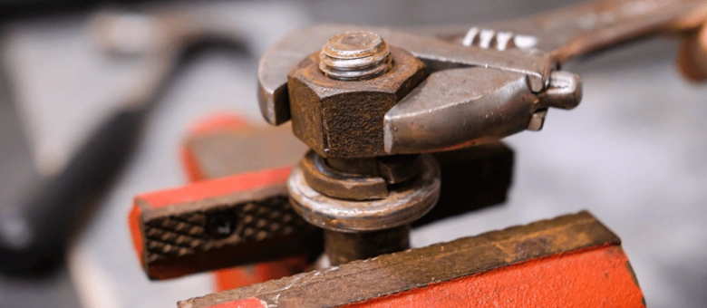 Rusty bolt and wrench in vise for removal guide.
