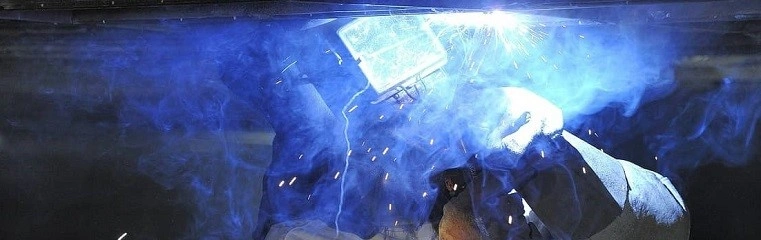 Svářeč v akci při svařování kovu s invertorem.