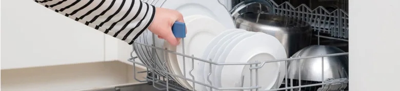 Ruka ukládá čisté talíře do myčky nádobí.