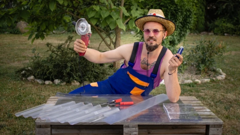 Muž řezá polykarbonátovou desku pilou na křemík venku.