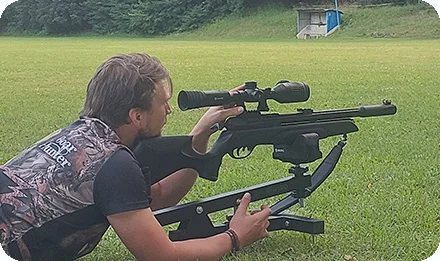 Muž namířený vzduchovkou na terč v areálu pro lov.