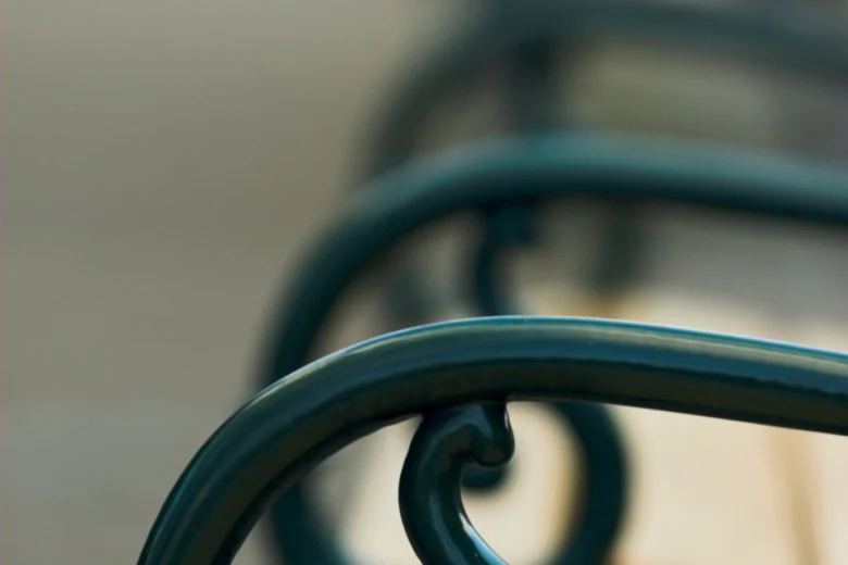 Detail zobrazení natřené kovové zábradlí na lavičce.