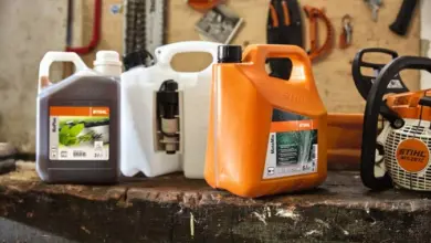 Nádrže s benzinem pro motorovou pilu značky Stihl na dřevěné ploše.