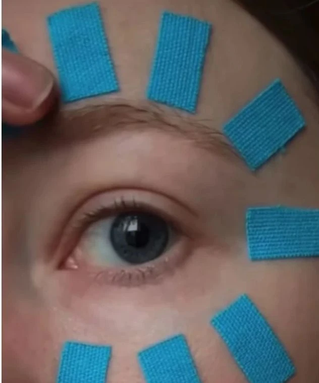Bluá tejpová páska aplikovaná kolem oka pro péči o pleť.