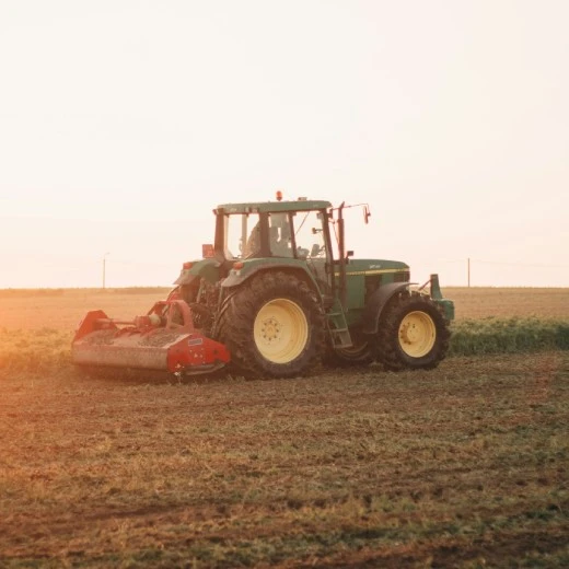 Traktor s připojeným pluhem při práci na poli.