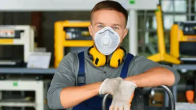 Pracovník v respirátoru s ochrannými sluchátky na tovární lince.