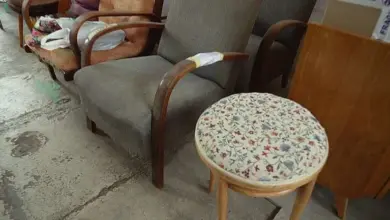 Čalouněný křeslo s dřevěným rámem a malý stůl v květinném vzoru.