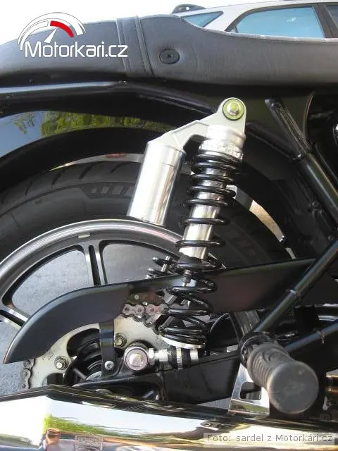 Černá pružina na motocyklovém tlumiči v detailu.