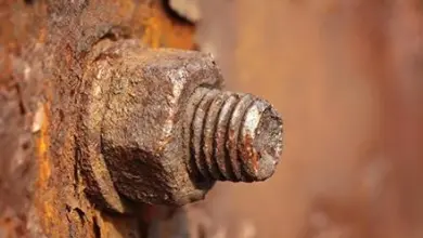Rusty bolt and nut stuck in corroded rusty metal.