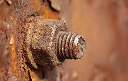 Rusty bolt and nut stuck in corroded rusty metal.