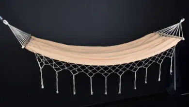 Hotový závěsný houpací sít z bílého macramé na tmavém pozadí.