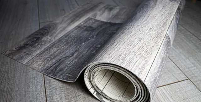 Svinutý list podlahového materiálu s dřevotiskem na stávající podlaze.