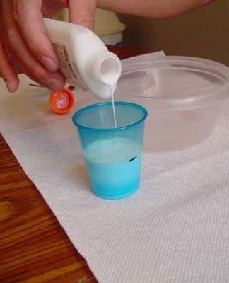 Nalévání bílého lepidla do modrého měřicího poháru.