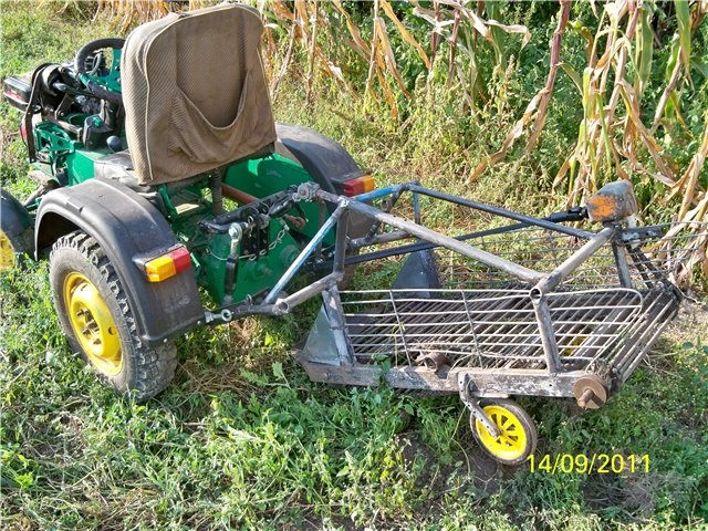 Zelený traktor s domlou vyrobeným vyorávačem brambor stojícím v kukurici.