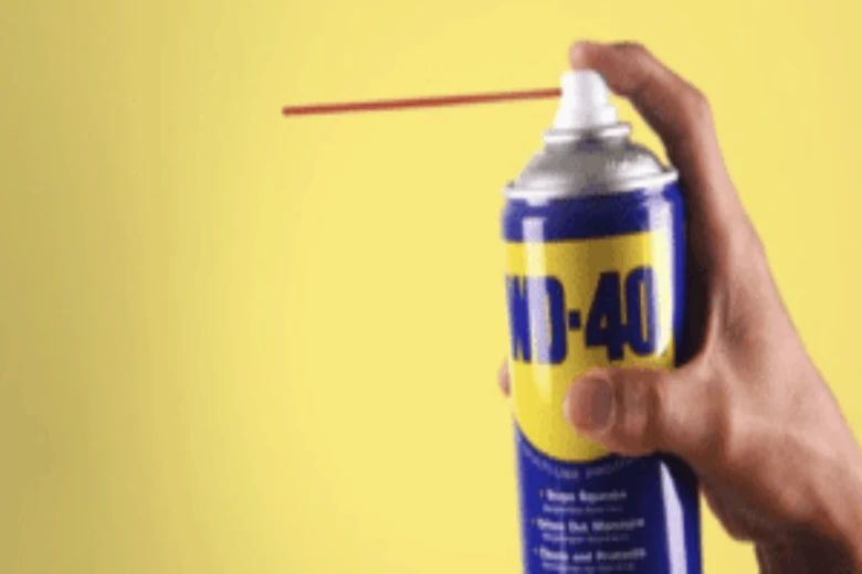 Ruka drží sprej WD-40 s prodlouženým tryskou na mazání zámků.