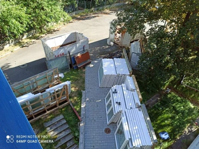 Nahromaděná stará plastová okna připravená k recyklaci venku.