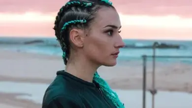 Žena s zelenými copánky na pláži při západu slunce.