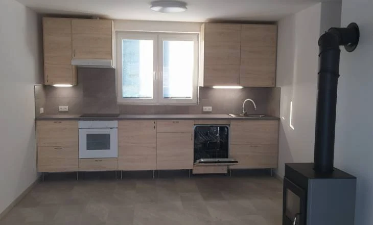 Moderní kuchyně s dřevěnými skříněmi a bílou spotřebiči.
