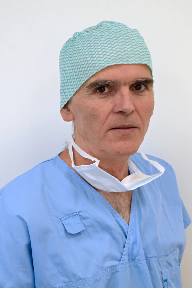 Muž v chirurgických šatech s rouškou na krku.