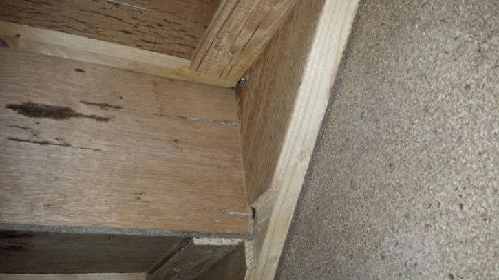 Detail dřevěného schodiště s viditelnými spoji v rohu.