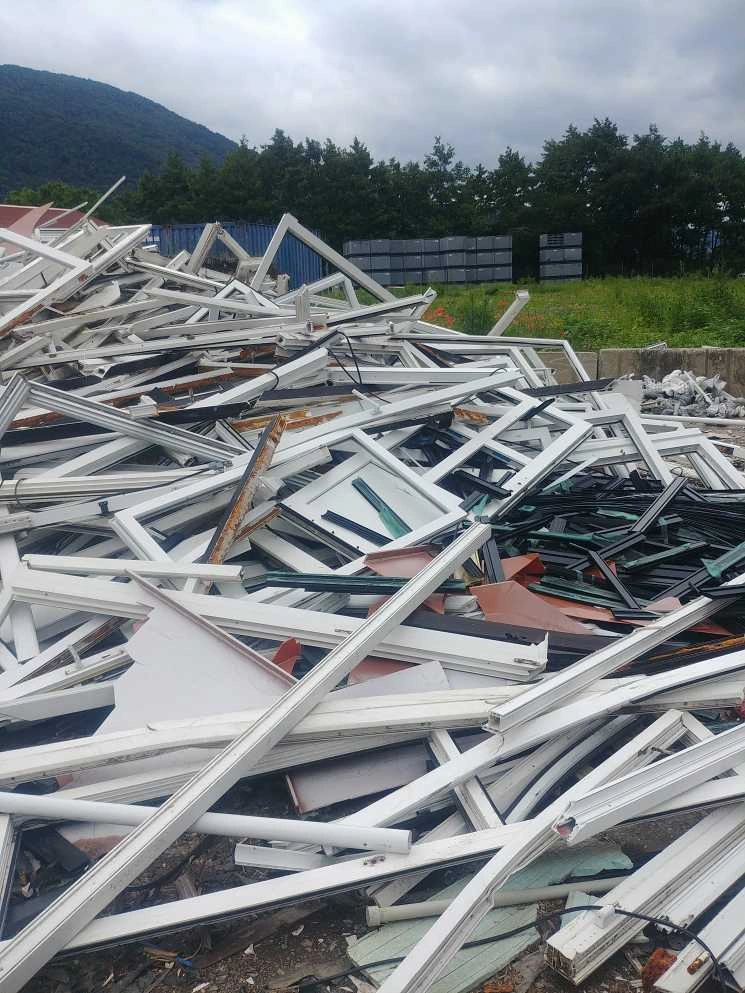 Hromada starých plastových oken připravená k recyklaci.