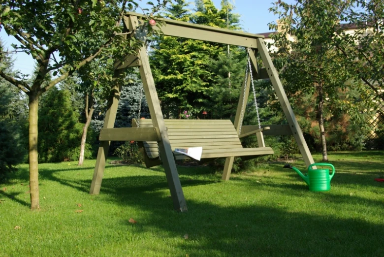Hotová dřevěná houpačka z klád v zahradě s trávníkem.