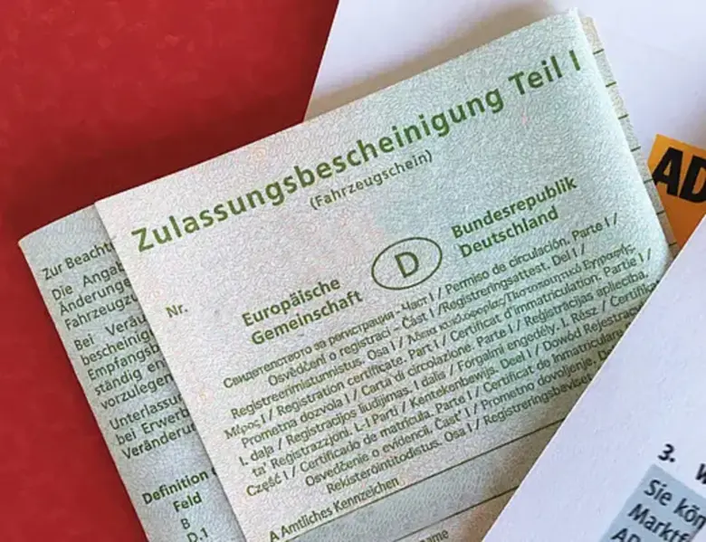 Německý doklad o registraci vozidla na červeném pozadí.