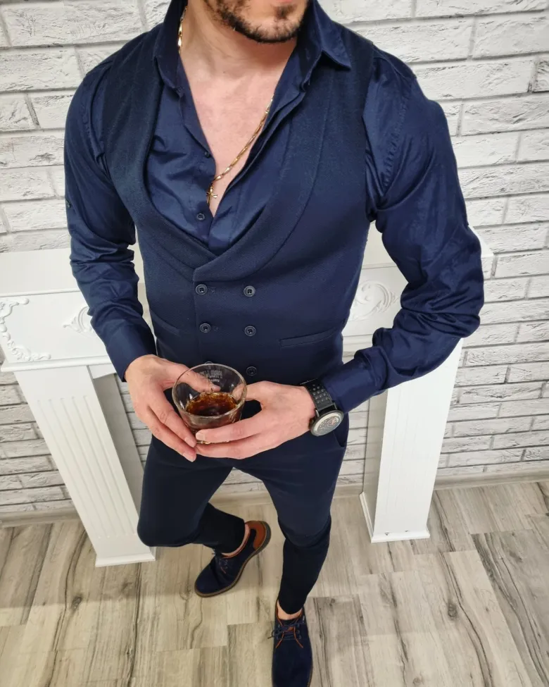 Muž v modrém saku a košili držící skleničku whisky.
