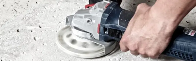 Ruční bruska s kotoučem na betonu při práci.