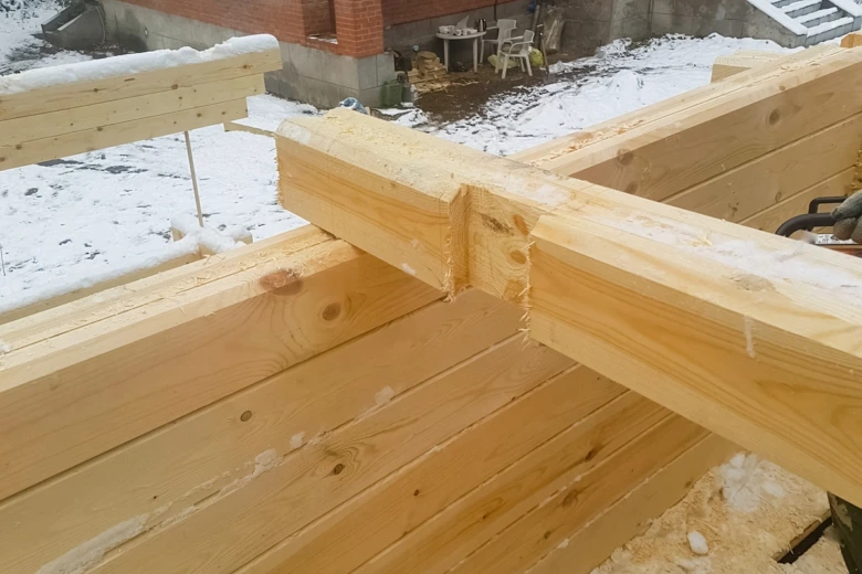 Spojení dřevěných trámů pomocí klínového spoje na stavbě.