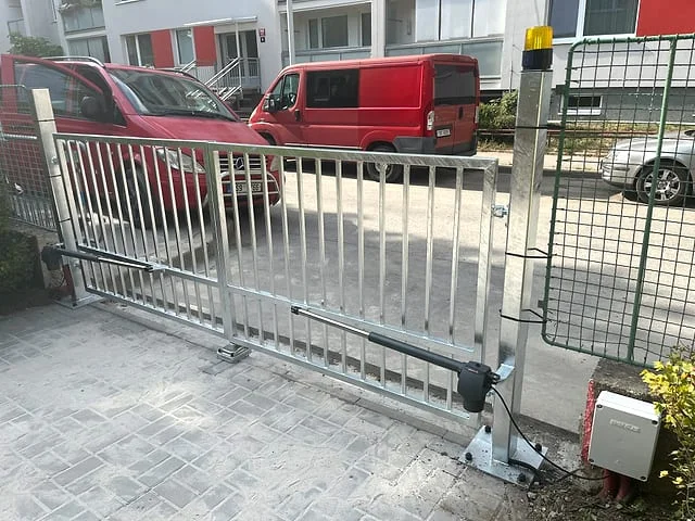 Posuvná kovová brána pro dvůr s viditelným mechanismem a motorem.