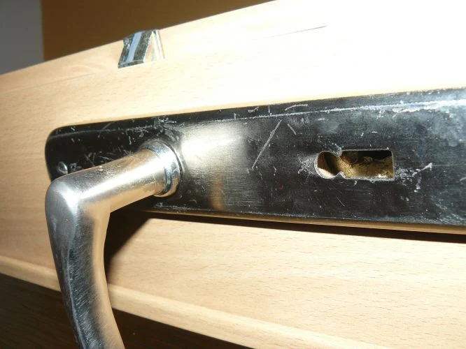 Detail interiérové kliky na dřevěných dveřích pro demontáž.